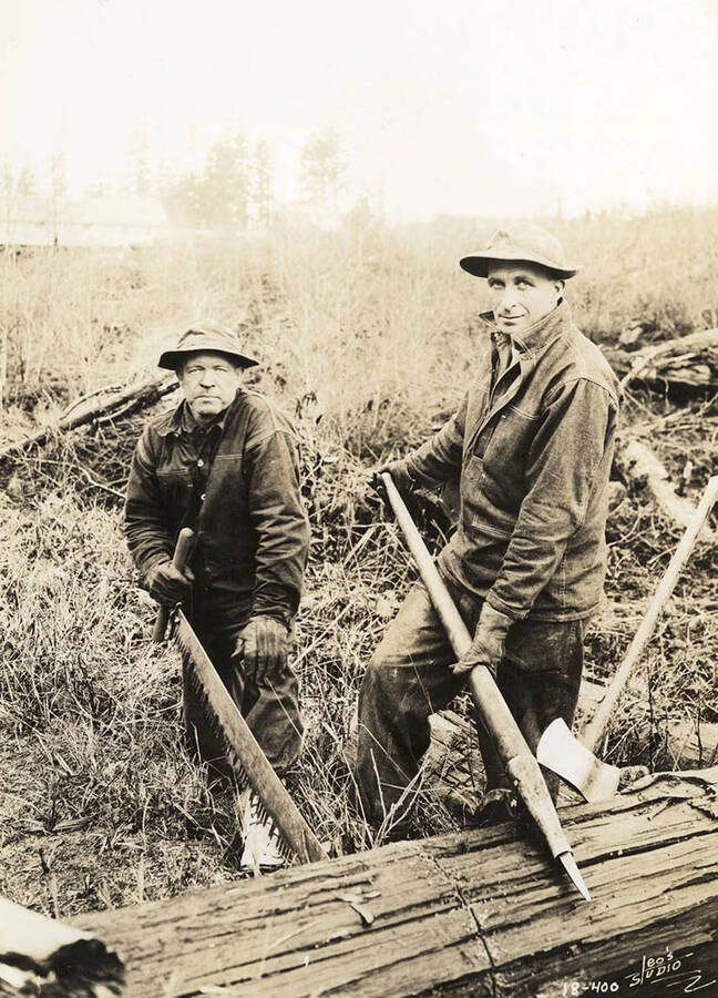 Two CCC men with a crosscut saw, peavies, and an ax working at Blow Down 2 CCC Camp, F-159. Back of photo reads: 'Blow Down Number 2'.