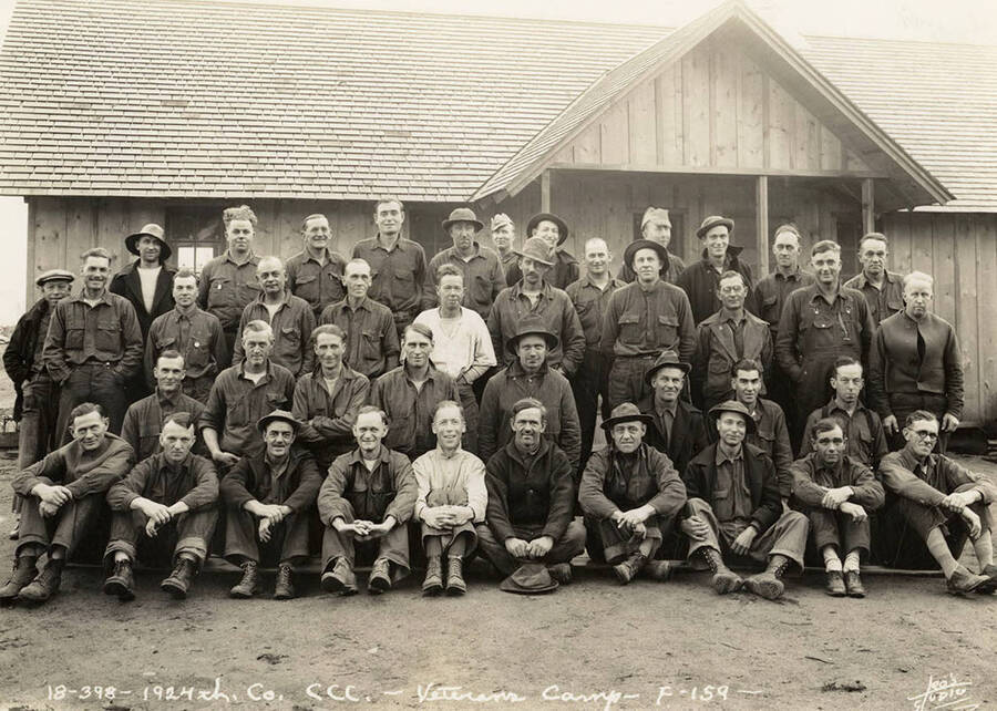 Group photo of the 1924th Company of the CCC in front of a building at Blow Down 2 CCC Camp, F-159. Writing on the photo reads: '1924th Company CCC Veterans Camp F-159'. Back of photo reads: 'Blow Down Number 2'.