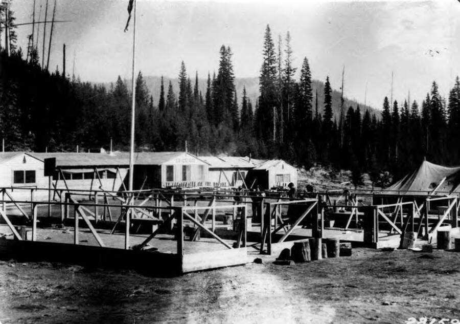 CCC men standing in half dismantled barracks at Camp Packer Meadows, Lolo National Forest, Aug. 1933. Writing on the building says: 'CO. 1251 CCC'.