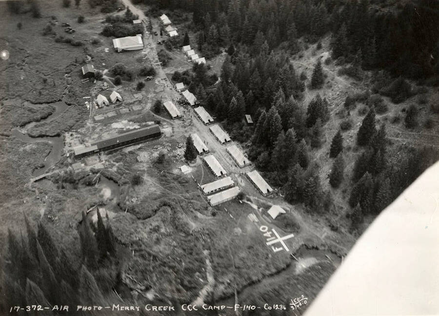 Aerial view of Merry Creek CCC Camp, F-140. Note geoglyph that reads: 'F-140'. Writing on the photo reads: ' Air photo Merry Creek CCC Camp F-140 Company 1236 Leo's Studio'. Back of photo reads: 'St. Joe'.