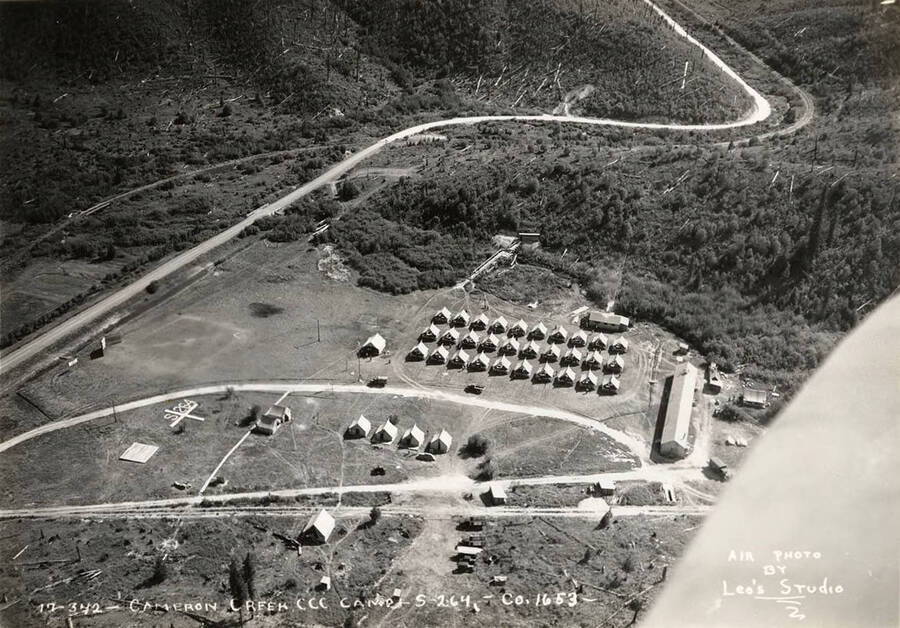 Aerial view of Cameron Creek CCC Camp, S-264. Note the geoglyph on the left-hand side of the camp that reads 'S-264'. Writing on the photo reads: 'Cameron Creek Camp S-264 Company 1653 Air photo by Leo's Studio'.