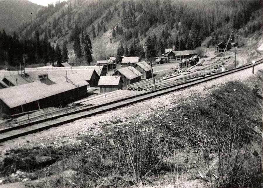 View of CCC Camp Marble Creek, F-117, and the Milwaukee Railroad tracks in the foreground. Back of photo reads: 'CCC Camp F-117 Marble Creek'.