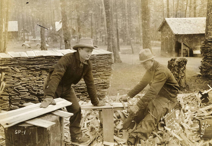 Two shingle weavers working and making shingles at CCC Camp Heyburn, Sp-1, Company 1995. Writing on the photo reads: 'SP-1 photo by Leo's Studio'. Back of photo reads: 'Heyburn'.