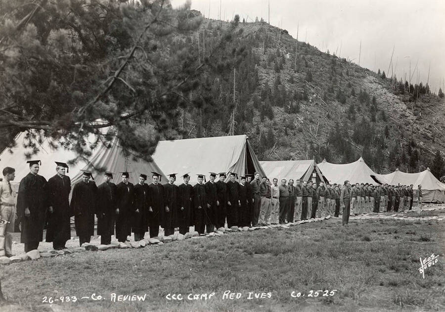Company 2525 review at Red Ives CCC Camp, F-184. CCC men can be seen standing in a row, some in graduation gowns, others in uniform. Writing on the photo reads: Company review CCC Camp Red Ives Company 2525 Leo's Studio'.
