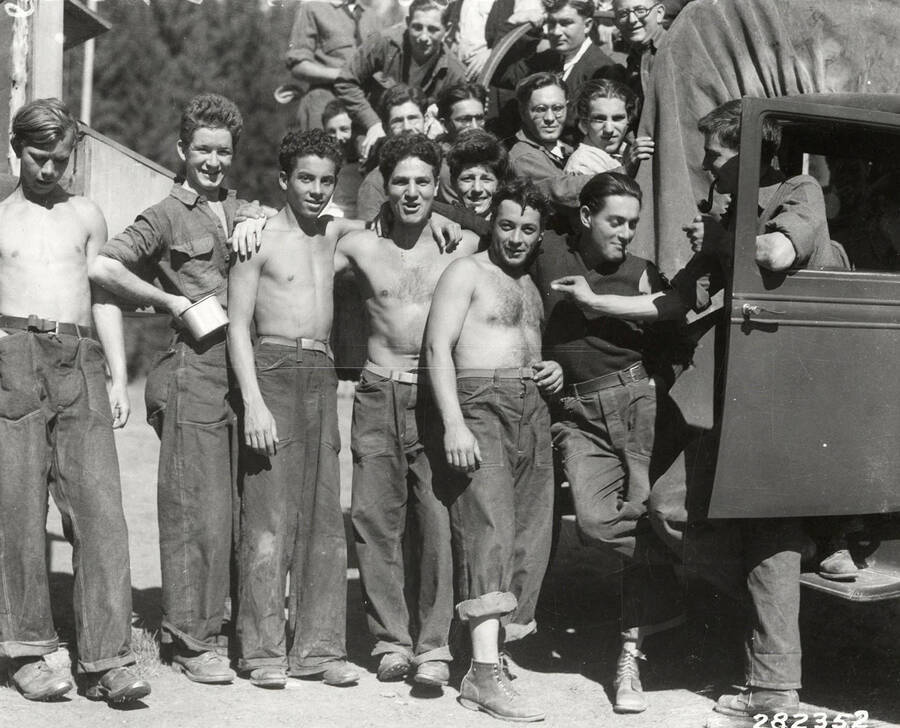 Group of CCC men posing near and on a truck at Emerald Creek CCC Camp, F-42 Company C-1202. They are on their way to Spokane to celebrate Yom Kippur. Back of photo reads: 'St. Joe National Forest. Group of boys at camp F-42. Photo by K.D. Swan September 1933.