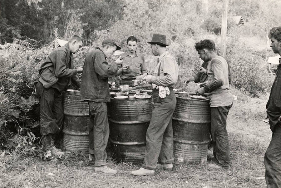 Group photo of a CCC fire crew resting and eating after fighting the Spirit Lake Fire. Stamp on back of photo reads: 'If this photo is reproduced credit must be given as follows: 'Photo by K.D. Swan, courtesy U.S. Department of Agriculture, Forest Service.''