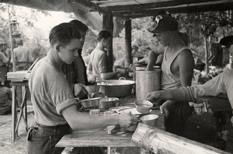 Photo of CCC fire crew members being served food in the chow line at the CCC Spirit Lake Fire Camp.