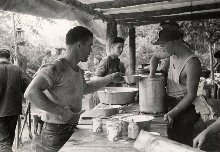 Photo of CCC fire crew members being served food in the chow line at the CCC Spirit Lake Fire Camp. Stamp on back of photo reads: 'If this photo is reproduced credit must be given as follows: 'Photo by K.D. Swan, courtesy U.S. Department of Agriculture, Forest Service.''