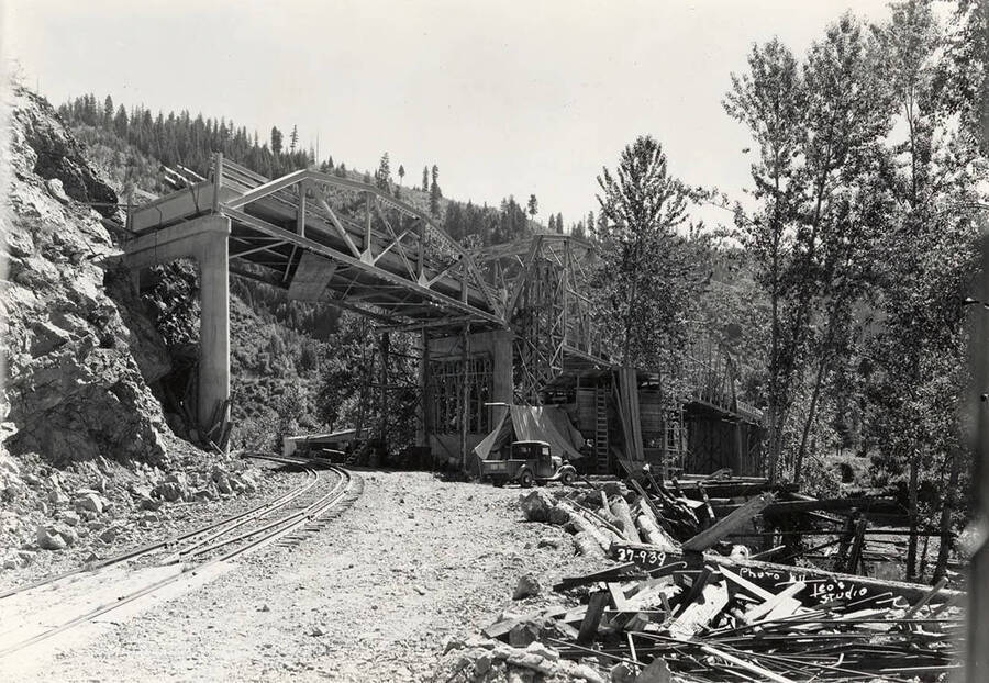 View of a bridge under construction on the St. Joe River. Bridge is being built by the CCC men at Camp Hess. Construction was started in 1938. Writing on the photo says: 'Photo by Leo's Studio'. Back of photo reads: 'CCC Camp Hess St. Joe'.