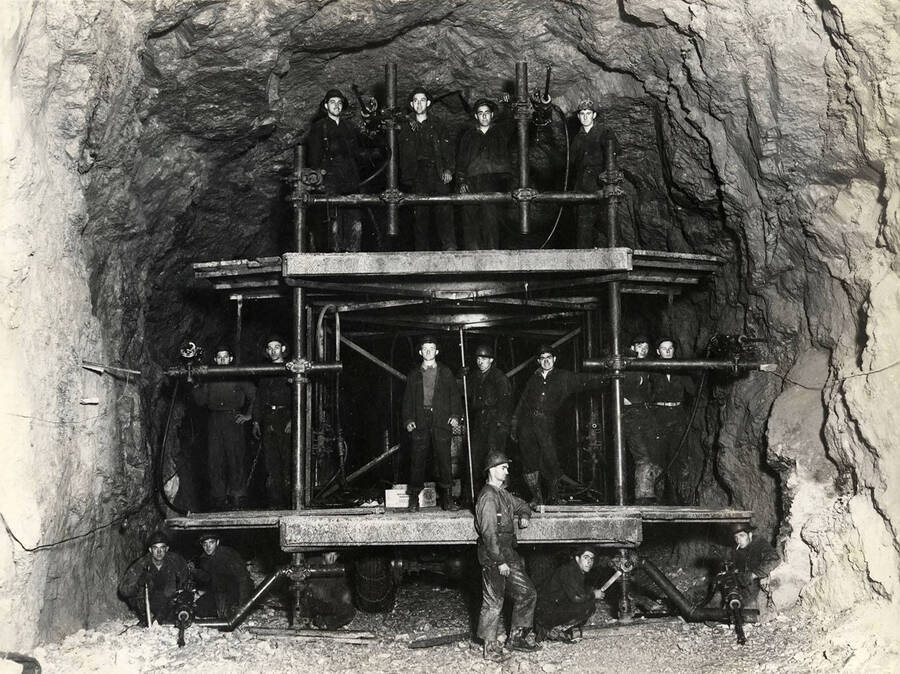Group photo of CCC men posed under and on scaffolding inside Fishhook Tunnel. Back of photo reads: 'Fishhook Tunnel E-Roads (e)-33 CCC 1938-1939'. Stamp on back of photo reads: 'If this photo is reproduced credit must be given as follows: 'Photo by K.D. Swan, courtesy U.S. Department of Agriculture, Forest Service.''