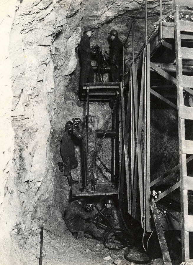 View of CCC men at work below and atop scaffolding inside the Fishhook Tunnel. Back of photo reads: 'Fishhook Tunnel E-Roads (e)-34 CCC 1938-1939'. Stamp on back of photo reads: 'If this photo is reproduced credit must be given as follows: 'Photo by K.D. Swan, courtesy U.S. Department of Agriculture, Forest Service.''