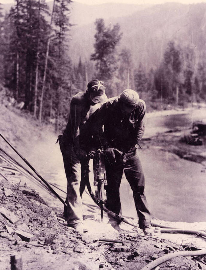 Two CCC men working on a jackhammer on the Sisson's Bridge project, drilling rock.