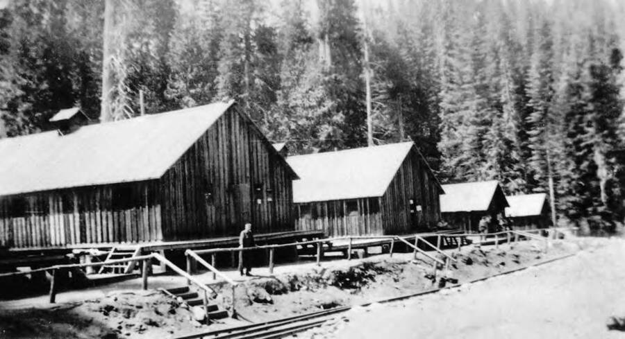 View of Washington Cabin CCC Camp, P-269, company 1654, near Washington Creek and Headquarters, Idaho with a railroad track running nearby.