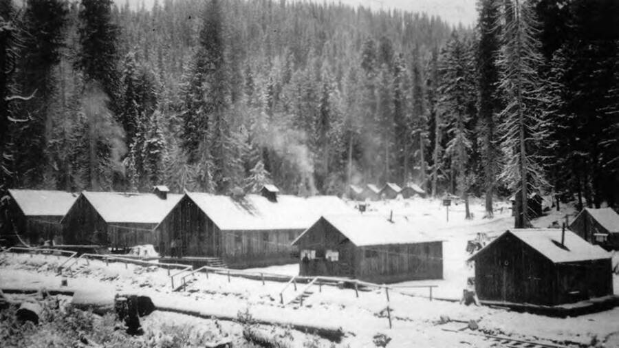 View of Washington Cabin CCC Camp, P-269, company 1654, near Washington Creek and Headquarters, Idaho with a railroad track running nearby.