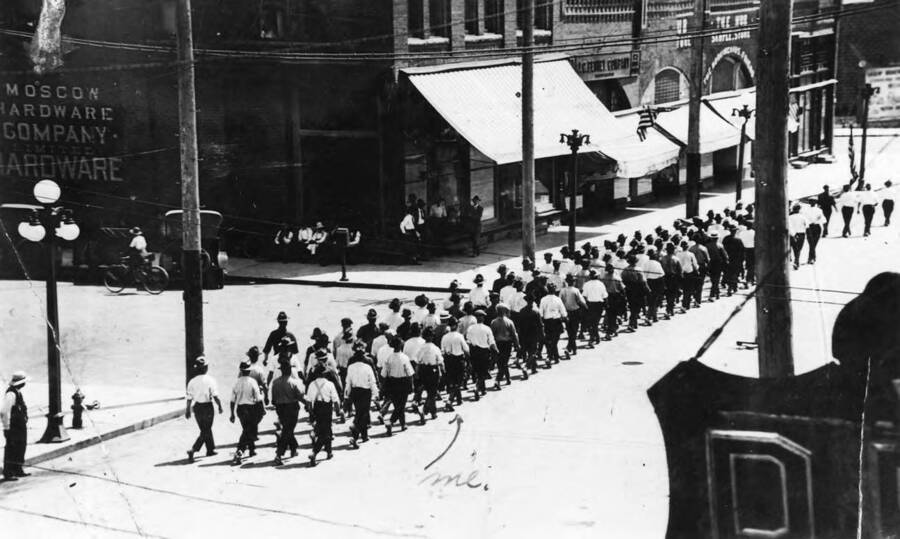 CCC company 1503 marching through Moscow, Idaho down Main St. There is a arrow drawn to one of the marchers labelled 'me'. This photo is a copy of a postcard. The back of the photo reads: '1-2-97 ask Keith who? Copy of Mike Fritz postcard.'