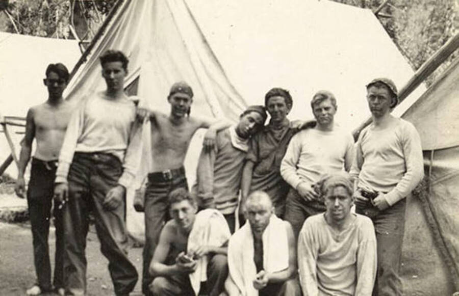 A group of CCC men stand in front of a tent at CCC Camp.