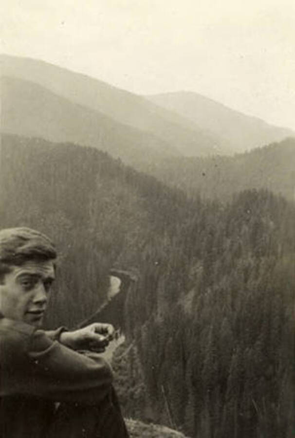 A CCC man sits in the foreground of a photo overlooking the landscape. Back of the photo reads: 'Sep. 1938'.