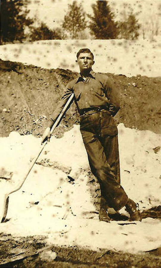 A CCC man poses with a shovel in the snow. CCC Camp Big Creek #2, F-132. Back of the photo reads: 'How to use a shovel!!'