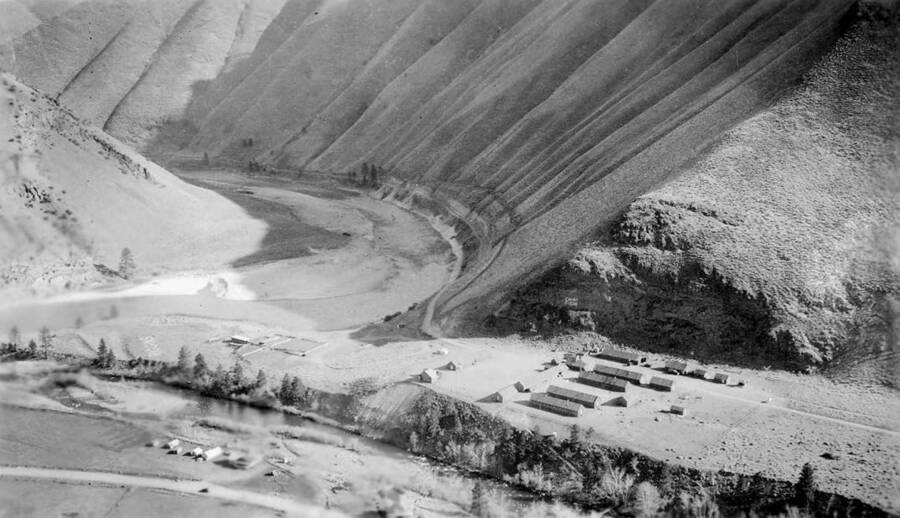 An aerial view of Camp Riggins On the valley floor near the mouth of the river it reads: 'Riggins' and on the cliff face : 'Camp F-106'.