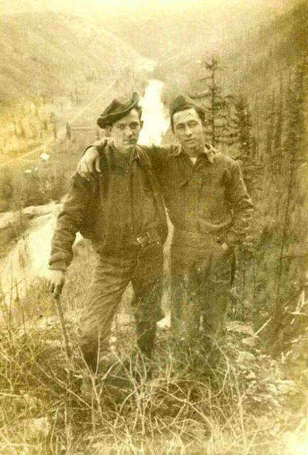 Two CCC men pose in front of the distant CCC Camp Big Creek #2, F-132 and the river.