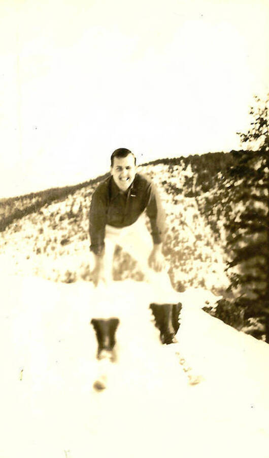 A CCC man poses on skis on a snow-covered mountain. CCC Camp Big Creek #2, F-132.