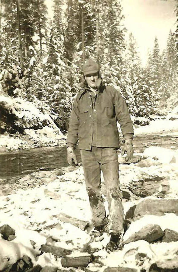A CCC man poses next to a snow-covered creek near CCC Camp Big Creek #2, F-132. Back of the photo reads: 'Wally Pietreyak from Steubenville area. CCC Co. 531 As you can see it is winter in Idaho.'