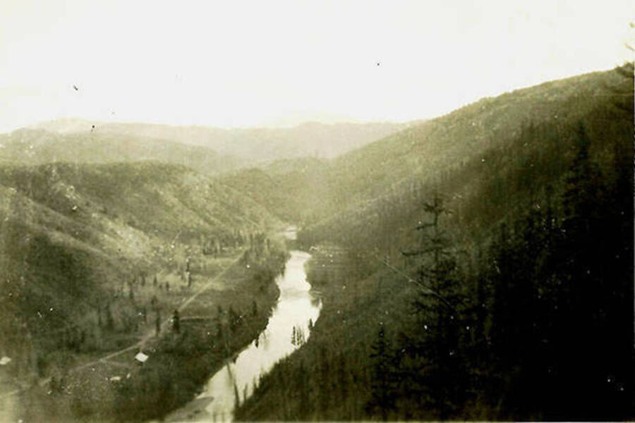 An overview of CCC Camp Big Creek #2, F-132, and the Coeur d'Alene River. Back of the photo reads: 'Camp area at lower left. Looking down on the North Fork of the Coeur d'Alene River.