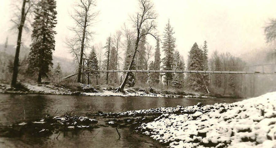 A view of the water line over Uranus Creek in the winter near CCC Camp Big Creek #2, F-132. The banks of the creek are covered in snow. Back of the photo reads: 'Good shot of our water line crossing Uranus Creek. It took some engineering skill to get this just right.'