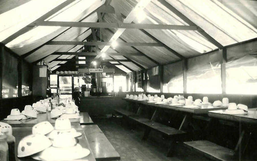 View of the mess hall and kitchen inside a tent structure at a spike camp of CCC Camp Big Creek #2, F-132. Back of the photo reads: 'Mess hall at spike camp'.