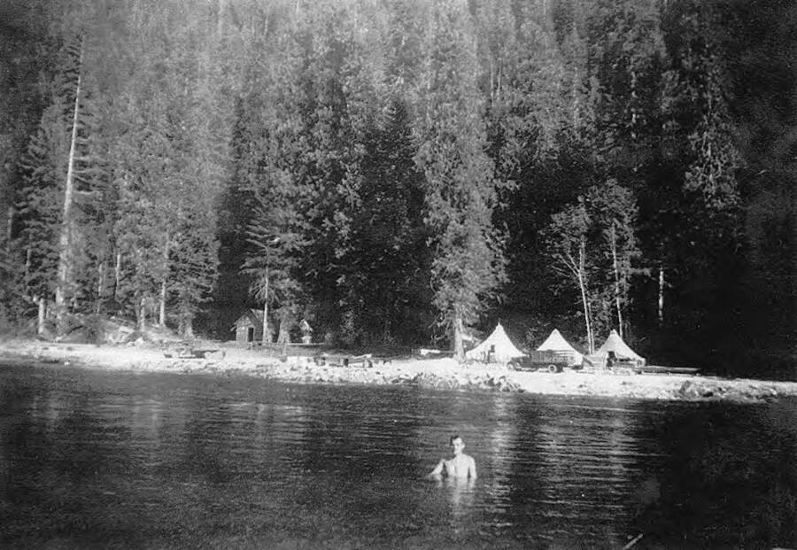 A CCC man swimming in the North Fork of the Clearwater River near Benton Creek and River Spike Camp (spike camp of Camp Black Bear P-262 at Headquarters, Idaho), downstream from Benton Creek Bridge. Bill Grybus is the man in the water. Photo was taken in August.