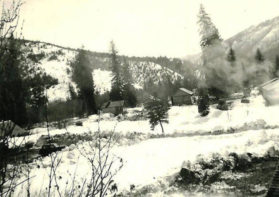 A photo of CCC Camp Big Creek #2, F-132 in the snow. Back of the photo reads: 'Paths shoveled out between buildings'.