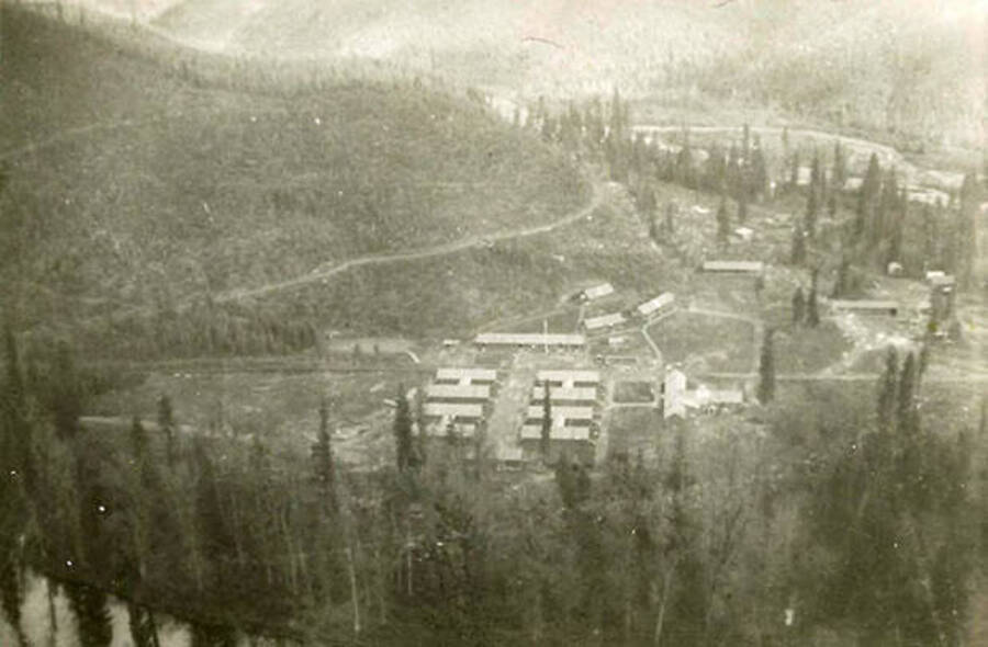 An overview of CCC Camp Big Creek #2, F-132 and the North Fork of the Coeur d'Alene River and the valley surrounding. Back of the photo reads: 'Taken from mountain above Camp Big Creek'.