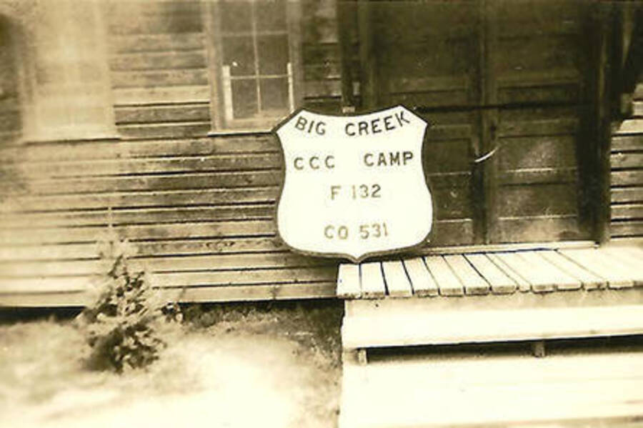 A sign that reads: 'Big Creek CCC Camp F-132 Co 531' leans against a building on a porch at Big Creek #2.