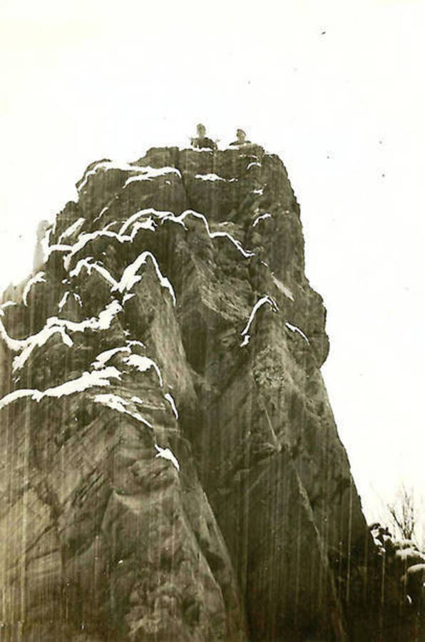 A shot of two CCC men atop a large snow-covered rock formation.