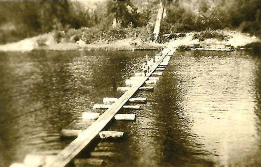 A CCC man runs across a bridge over the North Fork of the Coeur d'Alene River.
