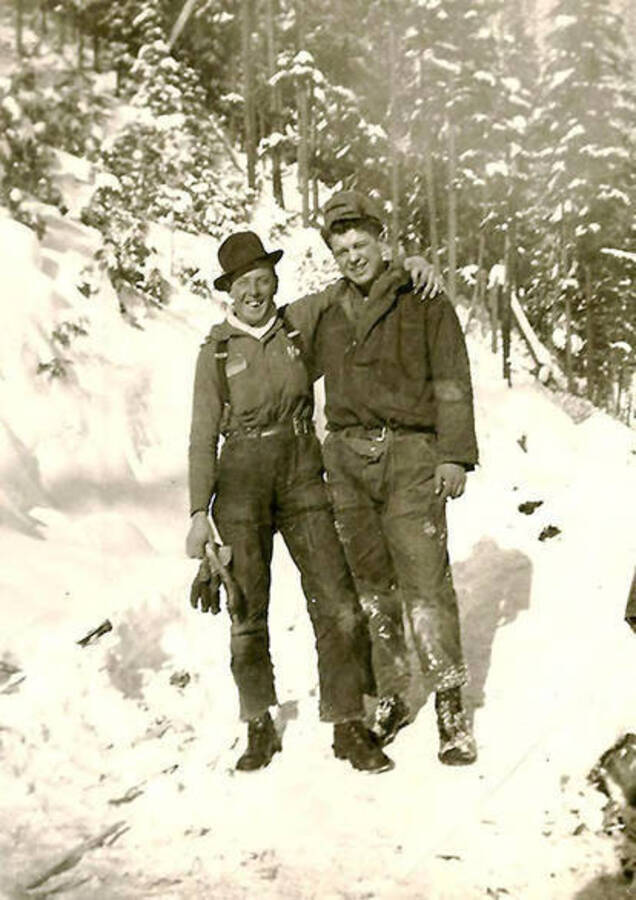 Two CCC men posing for a photo in the middle of the snow-covered woods. Back of the photo reads: 'Bill Whitley on left (our leader on woods crew)'.