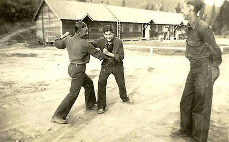 Three CCC man in CCC Camp Big Creek #2, F-132, the headquarters building in the background. Back of the photo reads: 'A little recreation in camp.'