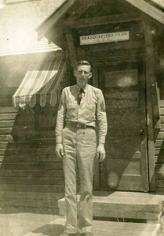 A CCC man stands in front of the door of the Headquarters building at CCC Camp Big Creek #2, F-132. The sign above the door reads: 'Headquarters CO. 531 C.C.C.' Back of the photo reads: 'Elmer Gerbach 1st Sgt of CO 531 Pritchard'