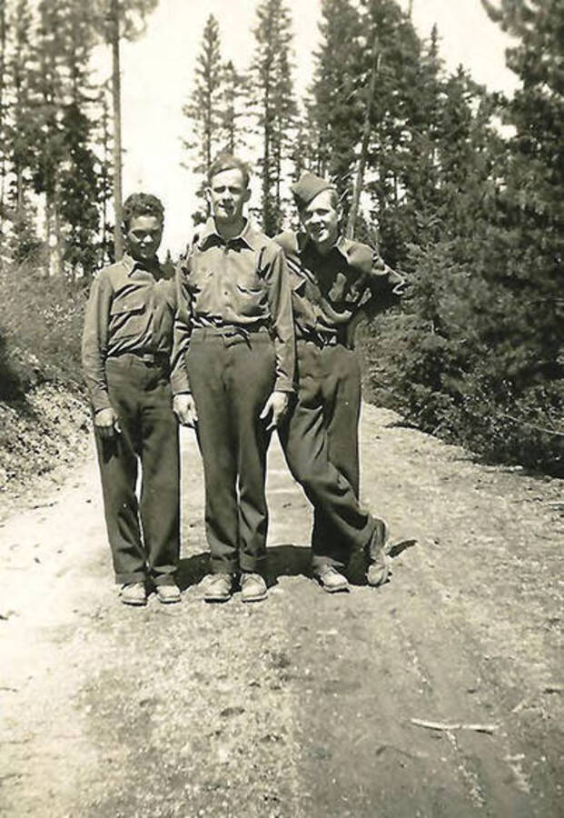 Three CCC man posed on a dirt road in the middle of the woods. Back of the photo reads: 'Lost in the woods!!'