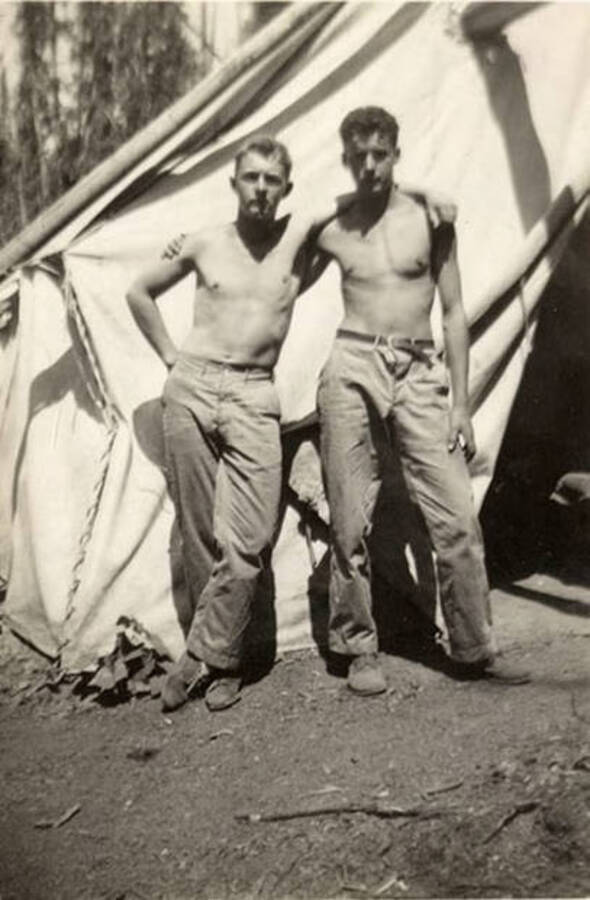 Two shirtless CCC men standing in front of a tent. Back of the photo reads: 'H. VanKirk C. Banku Bird Creek Camp St. Joe Forest, Idaho. August 29, 1938'