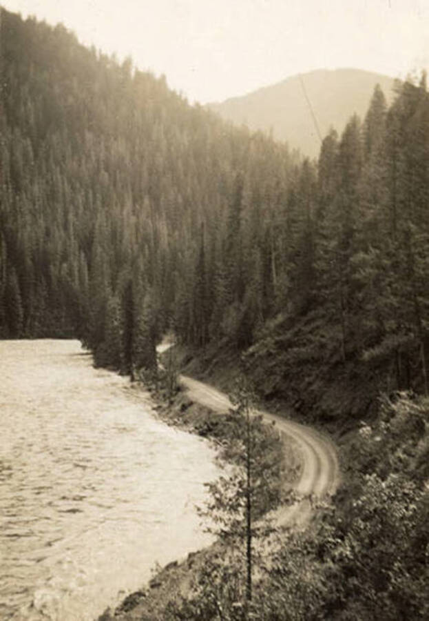 A view of a river, contextually likely to be the St. Joe River, with wooded hills rising in the background. Back of the photo reads: 'July 9, 1938'