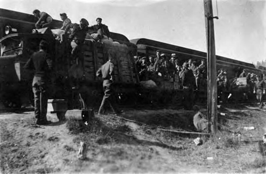 CCC men loading into a train. Writing next to the photo reads: 'Speeder from camp to headquarters'.