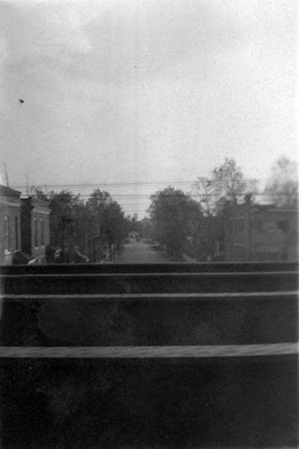 A Chicago, IL residential street, with trees down the sides can be seen from the train across several lanes of railroad tracks. Writing next to the photo reads: '