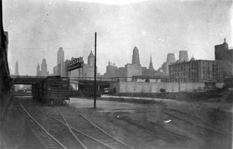 A view of a city with a railroad car and railroad tracks in the foreground. Writing below the photo reads: 'Altoona Wisconsin'.