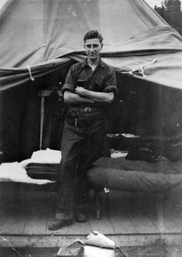 A photo of a CCC man standing in a tent in front of a cot.
