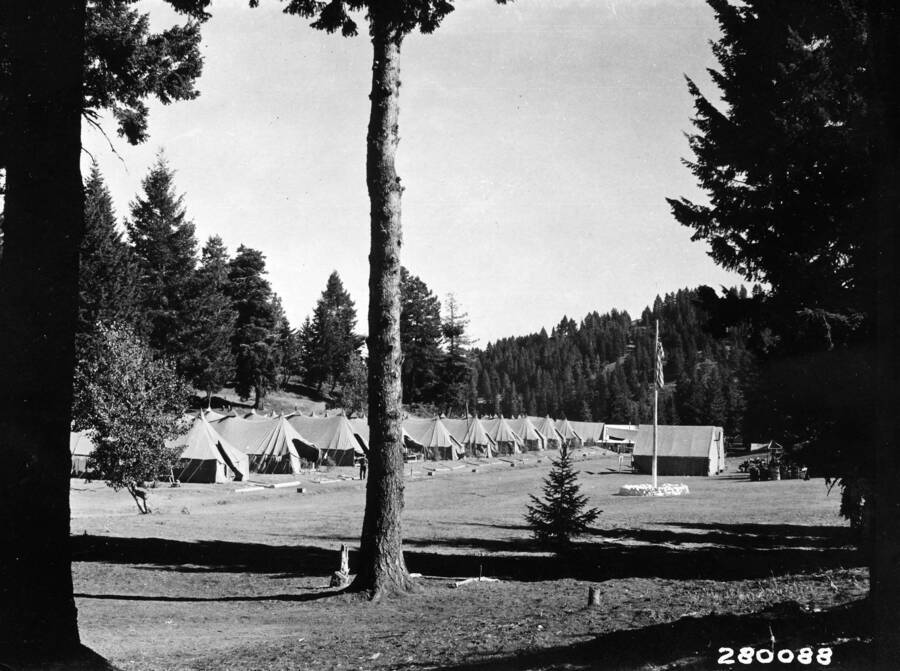 Rows of Tents and a flagpole in a forested area.