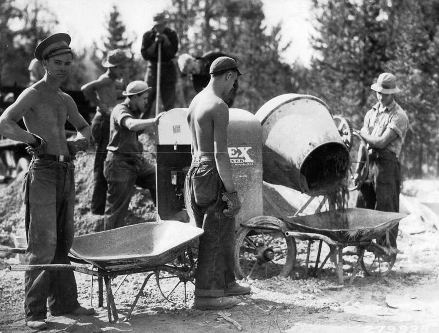 CCC Crew mixing cement and pouring it into wheelbarrows for a guard station at Redfish Lake, Sawtooth, Idaho. Photo taken in August. Writing above photo reads: 'CCC Civilian Conservation Corps Improvements, construction, Idaho. CCC Sawtooth, Idaho Mixing cement for guard station at Redfish Lake Taken by K.D. Swan Aug. 1933'.