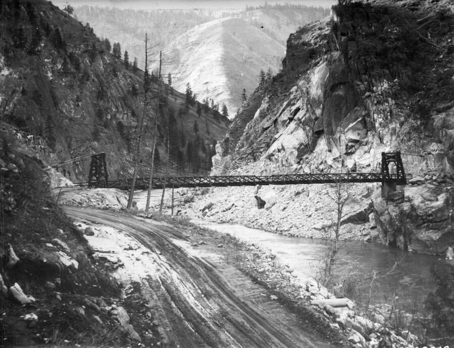 Manning Bridge above the Salmon River, built by CCC boys in 1934. There is also snow on the ground and tire tracks in the dirt road.