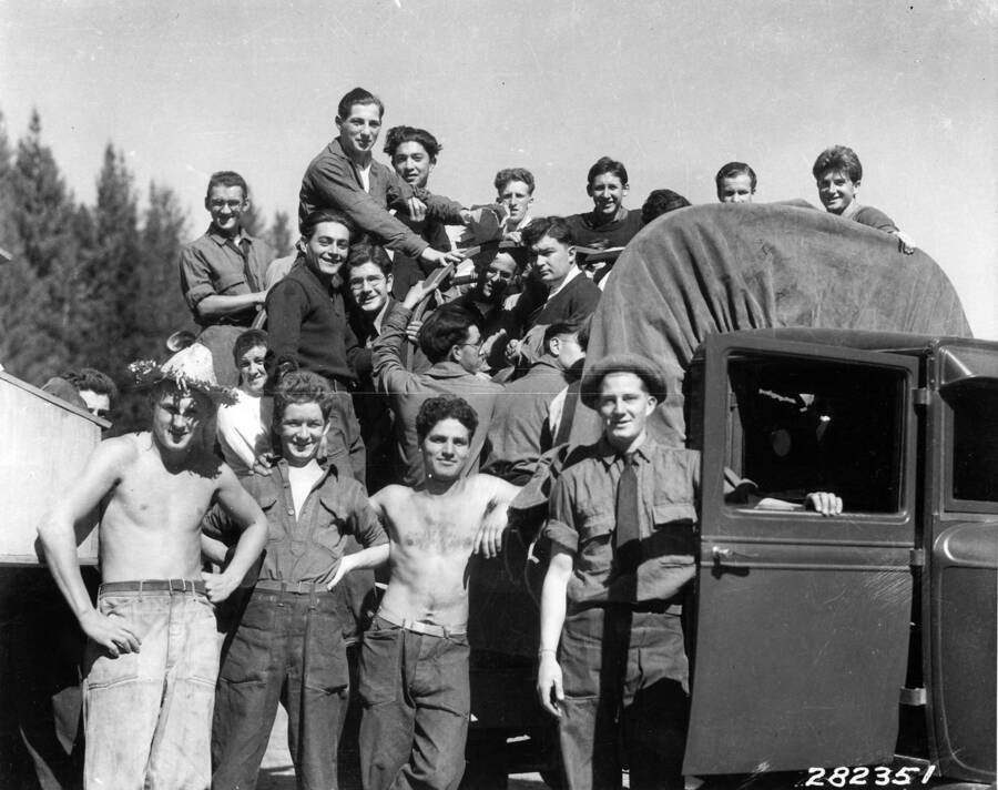 Group of CCC men posed around and on a truck at Emerald Creek CCC Camp, F-42 Company 1202. They are on their way to Spokane to celebrate Yom Kippur. Back of photo reads: 'St. Joe National Forest. Group of boys at camp F-42. Photo by K.D. Swan September 1933'.