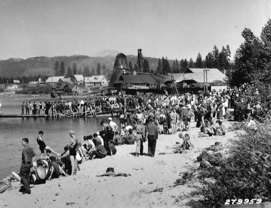 Contestants and spectators gather on the beach for the CCC water carnival and diving competition in McCall, Idaho. Back of photo reads: 'Water Carnival staged by three CCC Camps at McCall, Idaho. Near Idaho National Forest. Taken by K.D. Swan, 1933.'